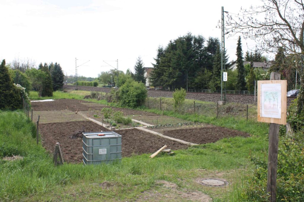 Der Vereinsgarten am Bahnübergang mit Infotafel und Wassertank