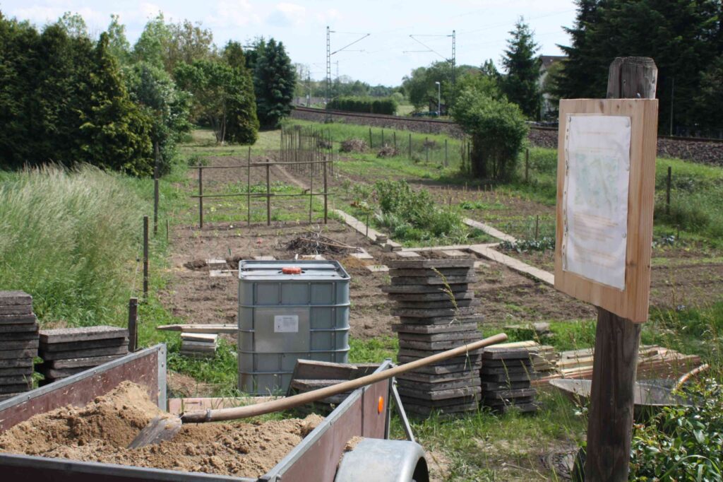 Infotafel, Baumaterial und Wassertank im Vereinsgarten
